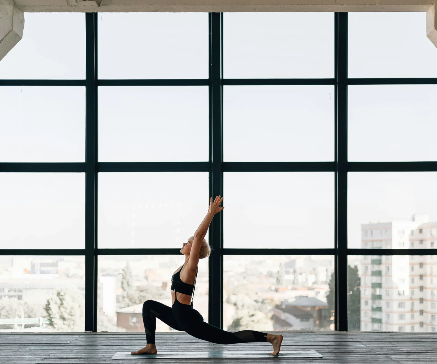 Mi az a Pilates? Nő Pilates gyakorlatot végez, kinyújtott karokkal városi stúdióban